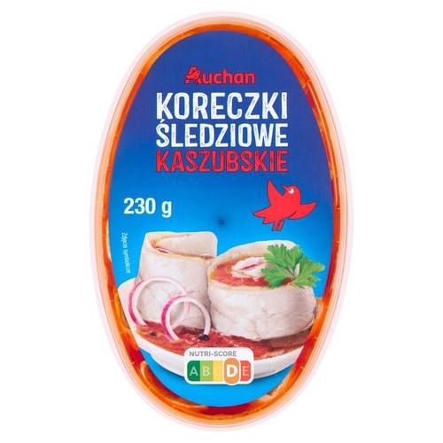 Produkt spożywczy: Koreczki Śledziowe Kaszubskie Auchan, 230 g. Na owalnym opakowaniu znajduje się niebieska etykieta z ilustracją dwóch koreczków śledziowych, podanych z czerwoną cebulą i zieloną pietruszką, zanurzonych w sosie.