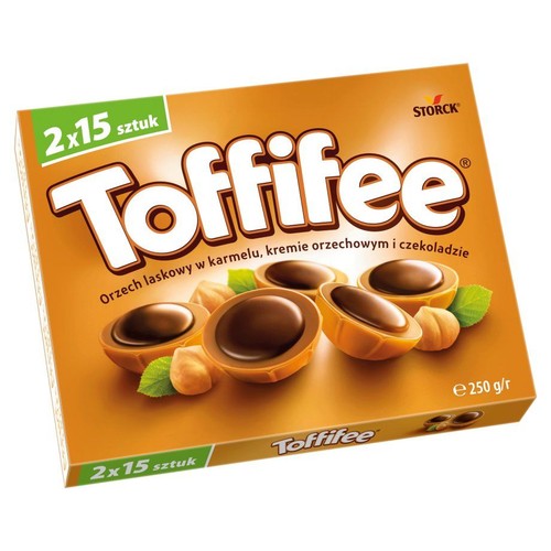 Brązowe opakowanie Toffifee marki Storck, zawierające 2x15 sztuk pralinek o łącznej wadze 250g. Na pudełku widnieje grafika przedstawiająca pralinki z orzechem laskowym w karmelu, kremie orzechowym i czekoladzie, otoczone orzechami i liśćmi.