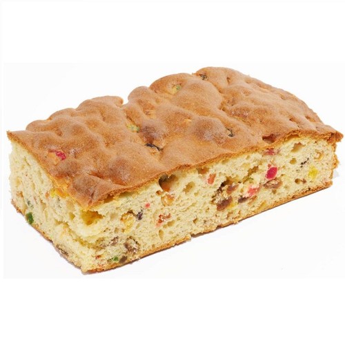 Pokrojony kawałek ciasta biszkoptowego z bakaliami. Wnętrze ciasta jest jasne, z licznymi, kolorowymi kawałkami kandyzowanych owoców i rodzynek. Górna warstwa ciasta jest upieczona na złoty kolor, z delikatnymi wgłębieniami.