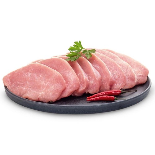Osiem plastrów surowego mięsa wieprzowego na ciemnym talerzu, udekorowane natką pietruszki i dwoma czerwonymi papryczkami chili.