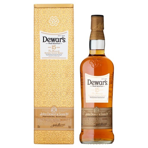 Butelka 15-letniej szkockiej whisky Dewar's True Scotch, The Monarch, z etykietą w kolorze kremowym i złotym. Obok stoi złote, ozdobne pudełko z wytłoczonym wzorem, logo marki i informacjami o produkcie John Dewar & Sons.