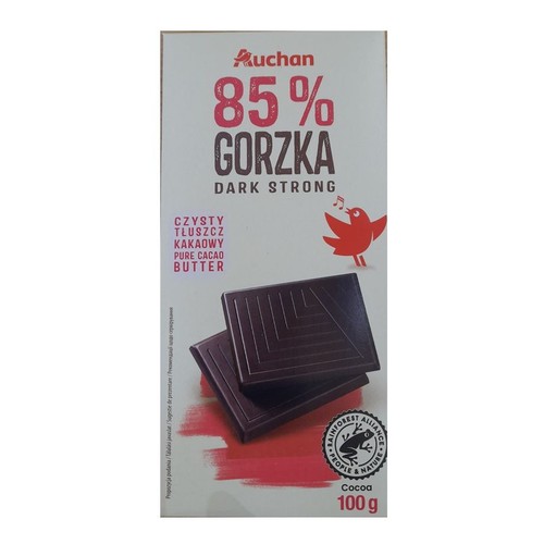Opakowanie czekolady gorzkiej Auchan 85% Dark Strong, 100 g. Na białym tle widnieje duży napis "85% GORZKA" oraz "CZYSTY TŁUSZCZ KAKAOWY". Poniżej grafika dwóch kostek ciemnej czekolady i logo Rainforest Alliance.