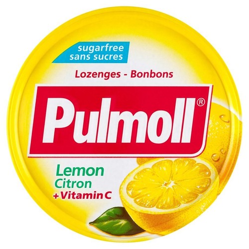 Okrągłe, żółte opakowanie pastylek Pulmoll bez cukru. Na czerwonym tle nazwa marki Pulmoll. Poniżej napis "Lemon Citron + Vitamin C" oraz grafika przekrojonej cytryny i liścia. Produkt to lozenges/bonbons.