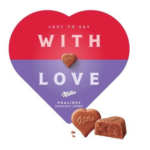 Produkt Milka Pralines Hazelnut Creme. Na pierwszym planie dwie czekoladki: jedna w kształcie serca z logo Milka, druga przekrojona, ukazująca orzechowy krem. W tle grafika w kształcie serca, czerwono-fioletowa, z napisem "Żeby powiedzieć z miłością".