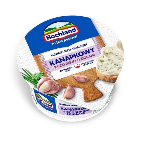 Opakowanie serka Hochland Kanapkowy z czosnkiem i ziołami. Na wieczku grafika czosnku, ziół i posmarowanej kromki chleba.