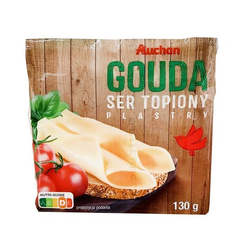 Auchan Ser Topiony Gouda w plastrach, 130 g. Na opakowaniu grafika sera na pieczywie z pomidorami i bazylią, jako propozycja podania.