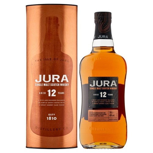 Jura Single Malt Scotch Whisky, leżakowana 12 lat, w szklanej butelce z czarną etykietą. Obok stoi miedziane opakowanie kartonowe z napisem "The Isle of Jura" i datą założenia 1810.